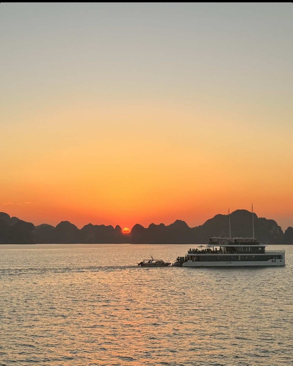 Video cover. Orange sunset over the limestone islands of Ha Long Bay, with a boat crossing the water.